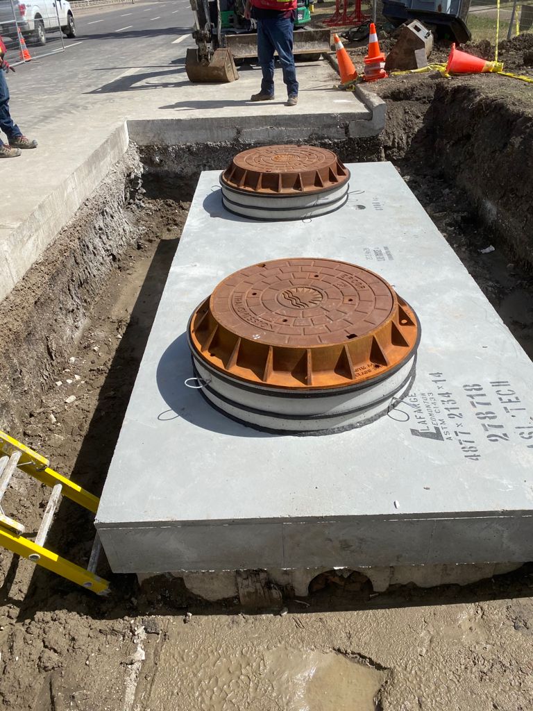 Precast concrete manhole vault with cast iron access covers installed in roadway