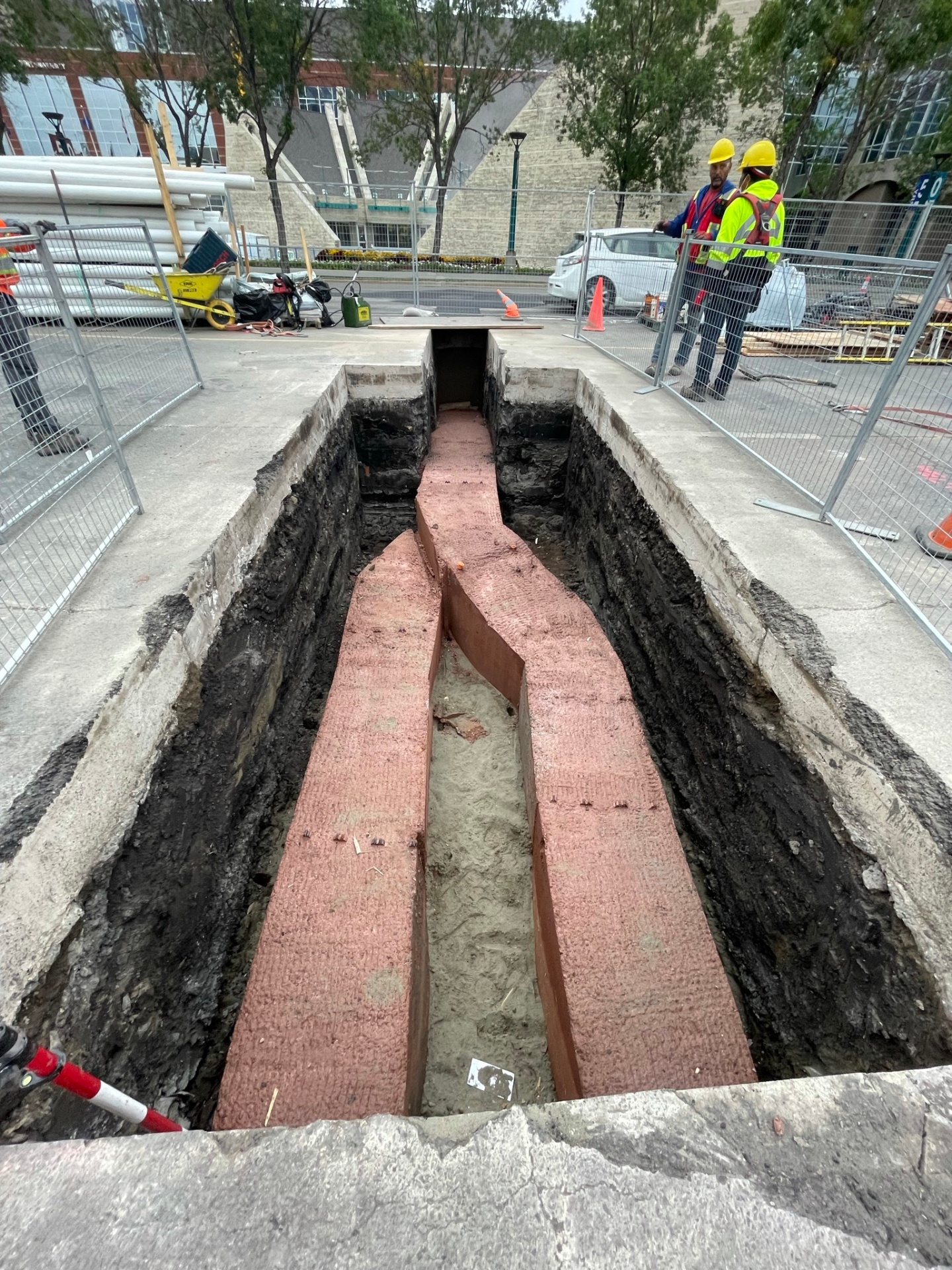 Open shored trench with red shoring plates and sand bedding ready for ductbank