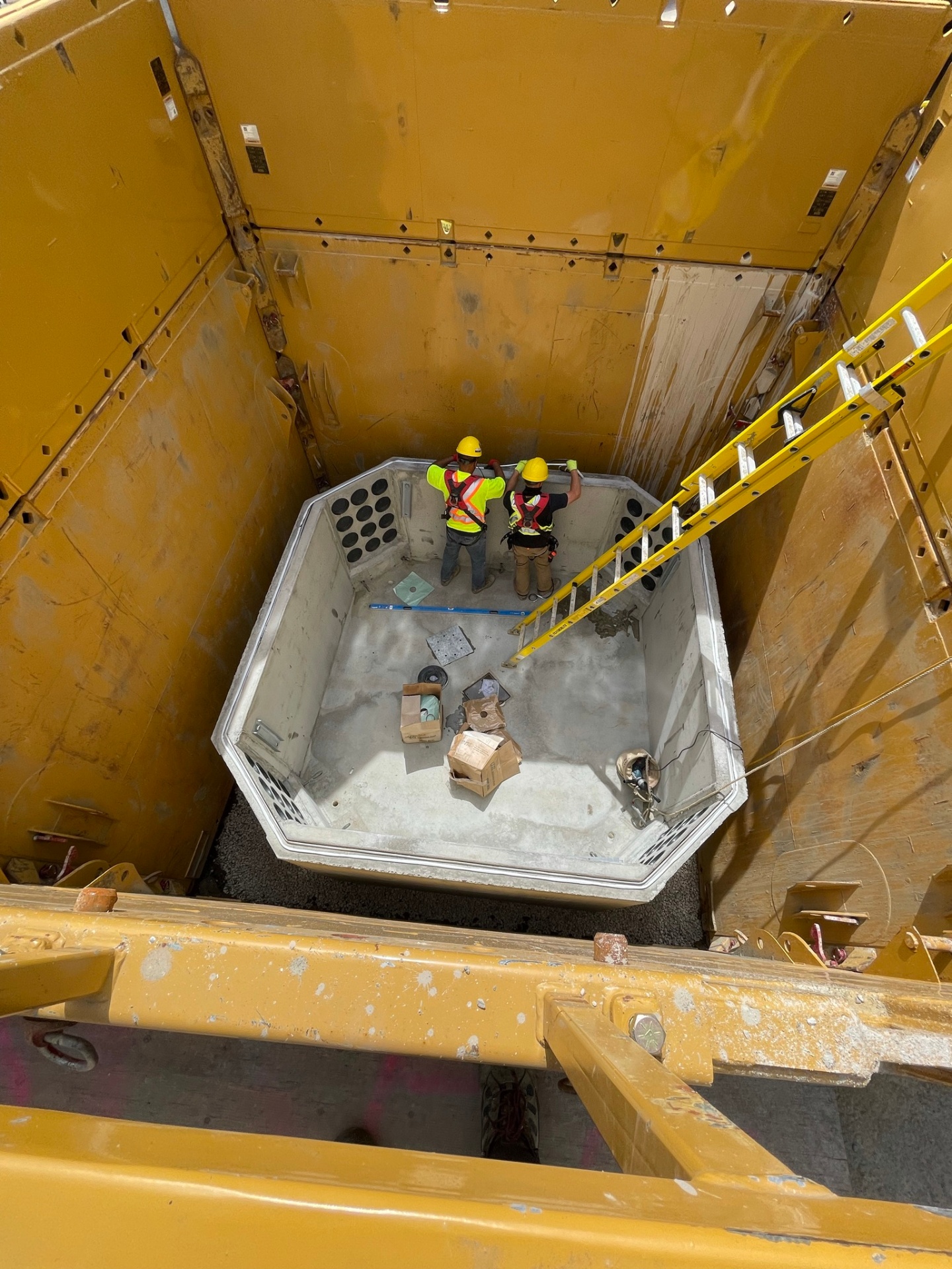 Precast concrete vault set inside shored excavation with crew aligning sections