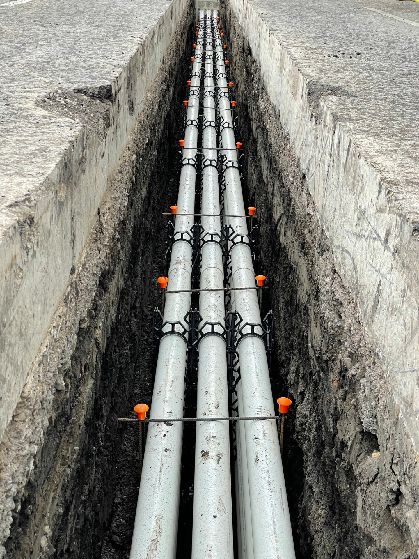 Multi-way PVC conduit bank with spacers and rebar in open trench