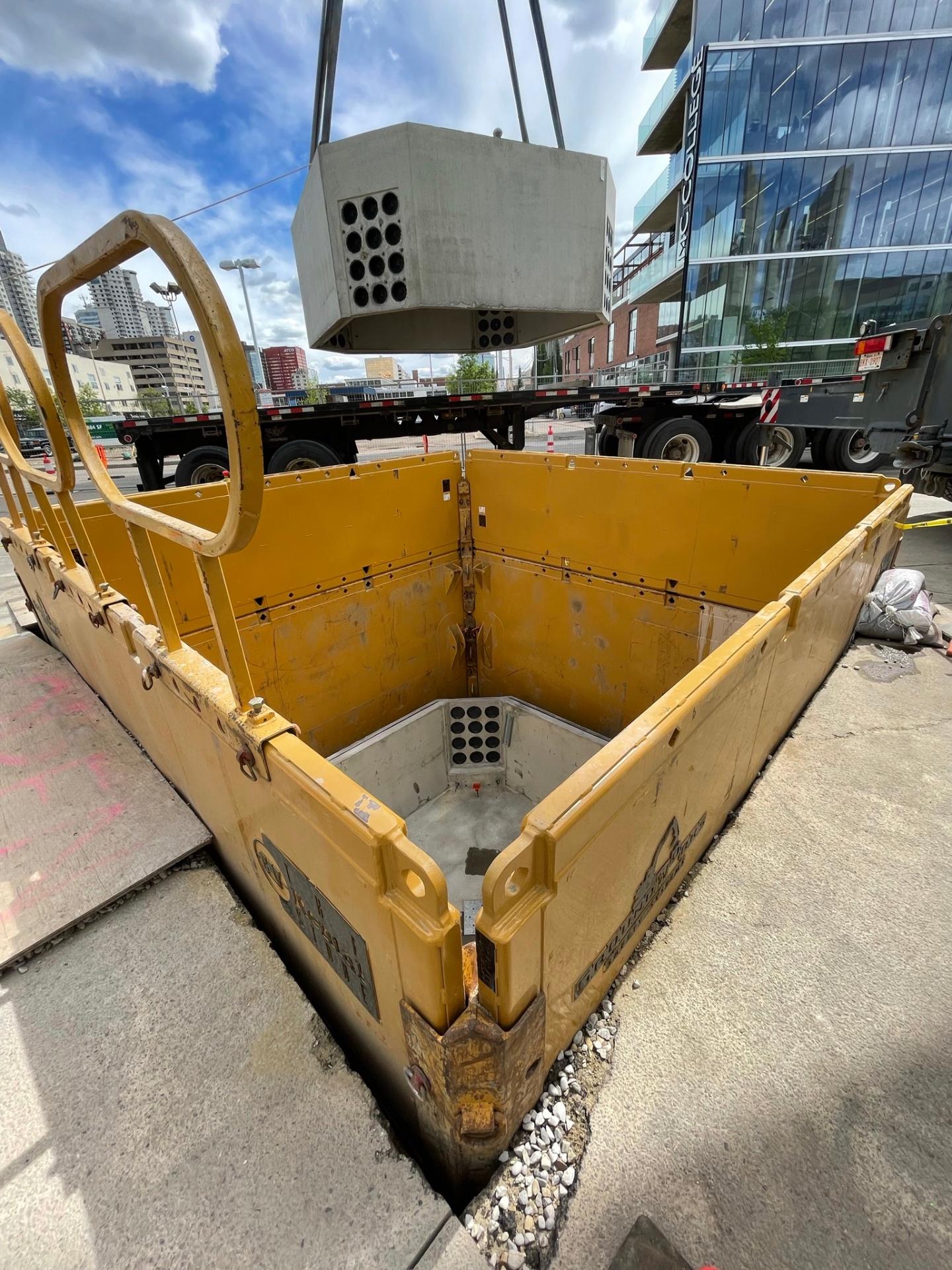 Crane setting precast concrete manhole vault into excavation