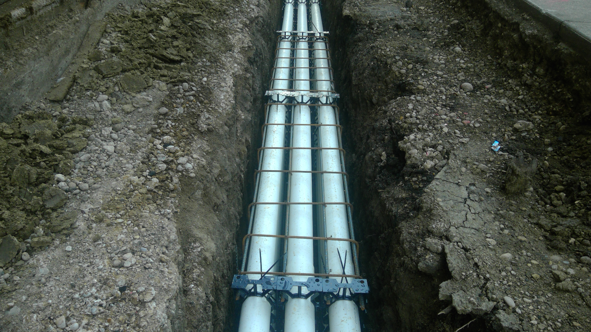 Multi-duct conduit bank with rebar bracing in open trench over water line
