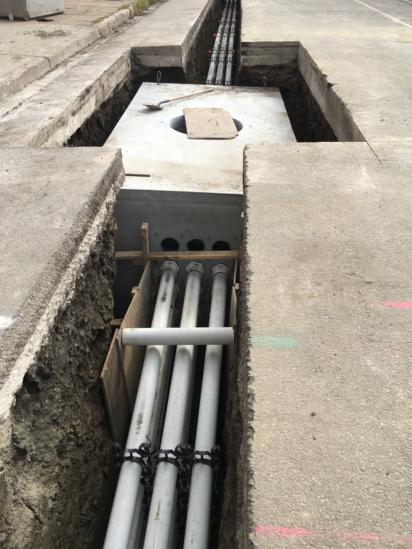 Precast concrete manhole vault with conduit entries in shored excavation