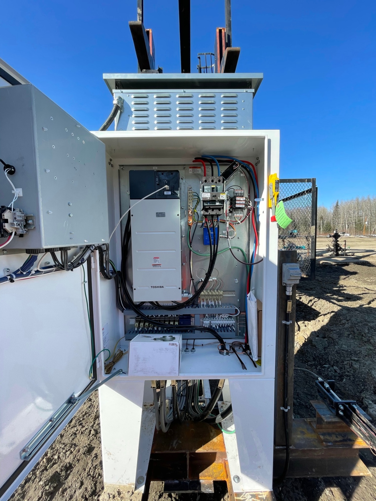Outdoor electrical control cabinet with VFD and terminal wiring at a wellsite