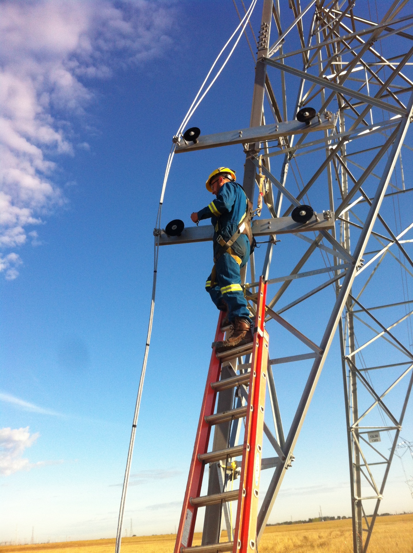 Technician working at height on a transmission tower stringing conductor