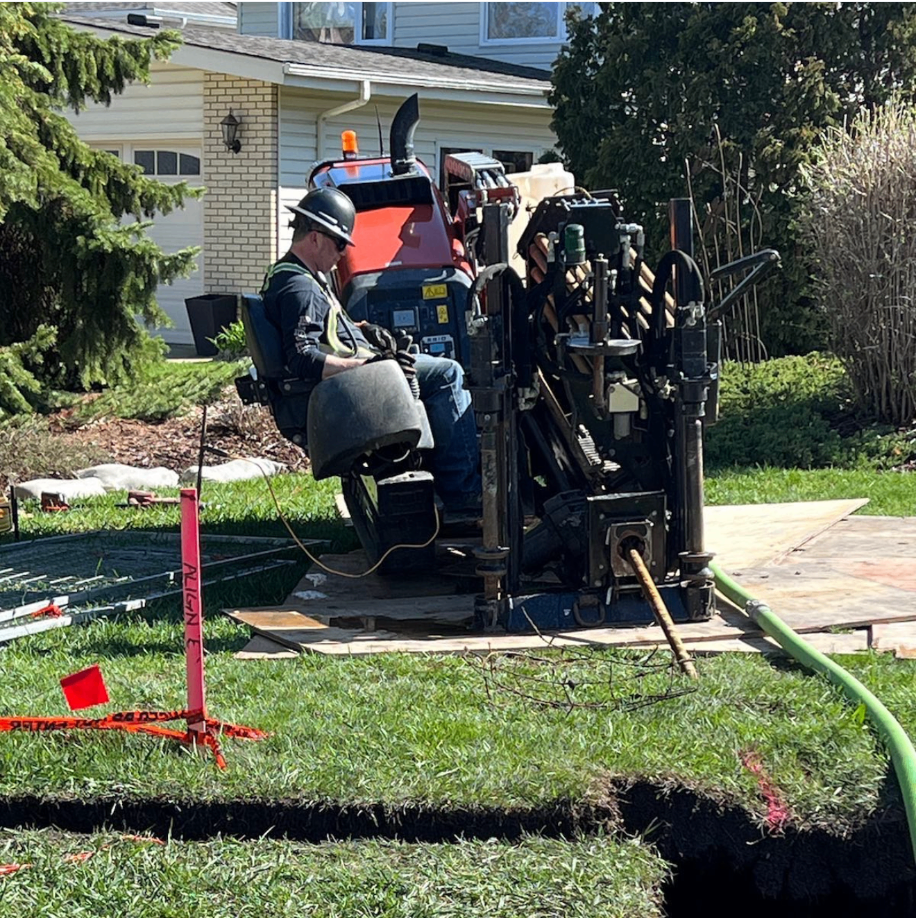HDD operator running compact directional drill rig in residential front yard