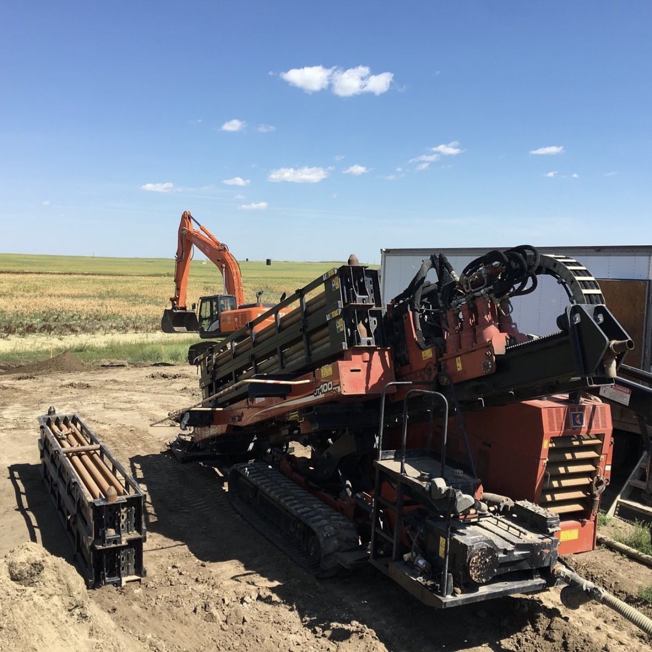 Large Ditch Witch HDD rig staged on rural cropland with excavator support