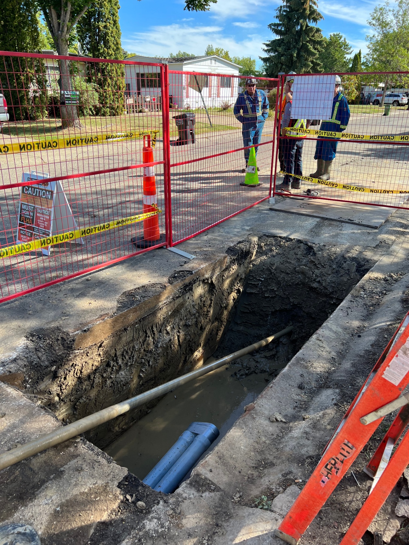 Trenchless utility crossing pothole with conduit exposed in fenced work zone