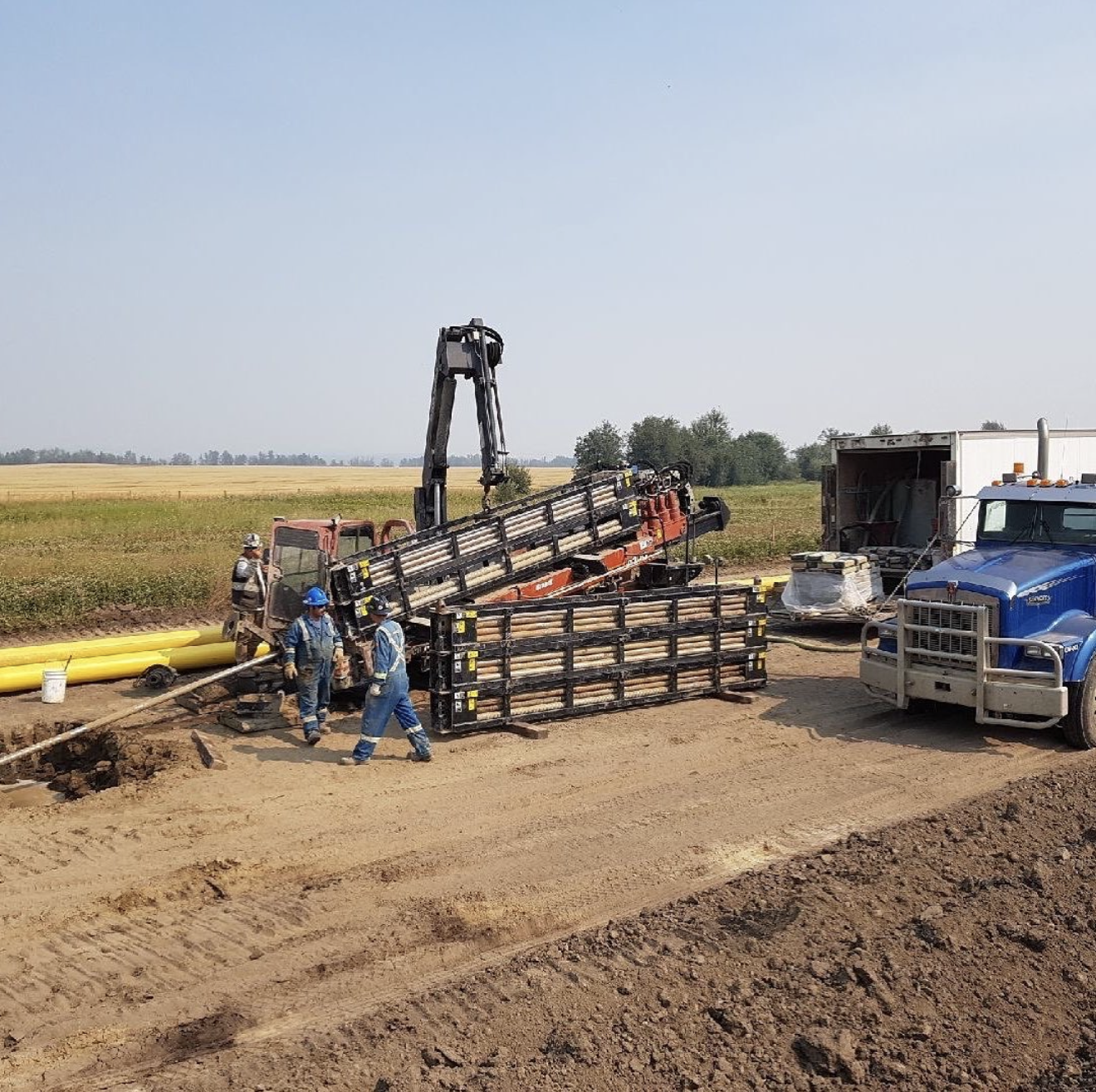 HDD crew loading drill rods on rig at agricultural field site