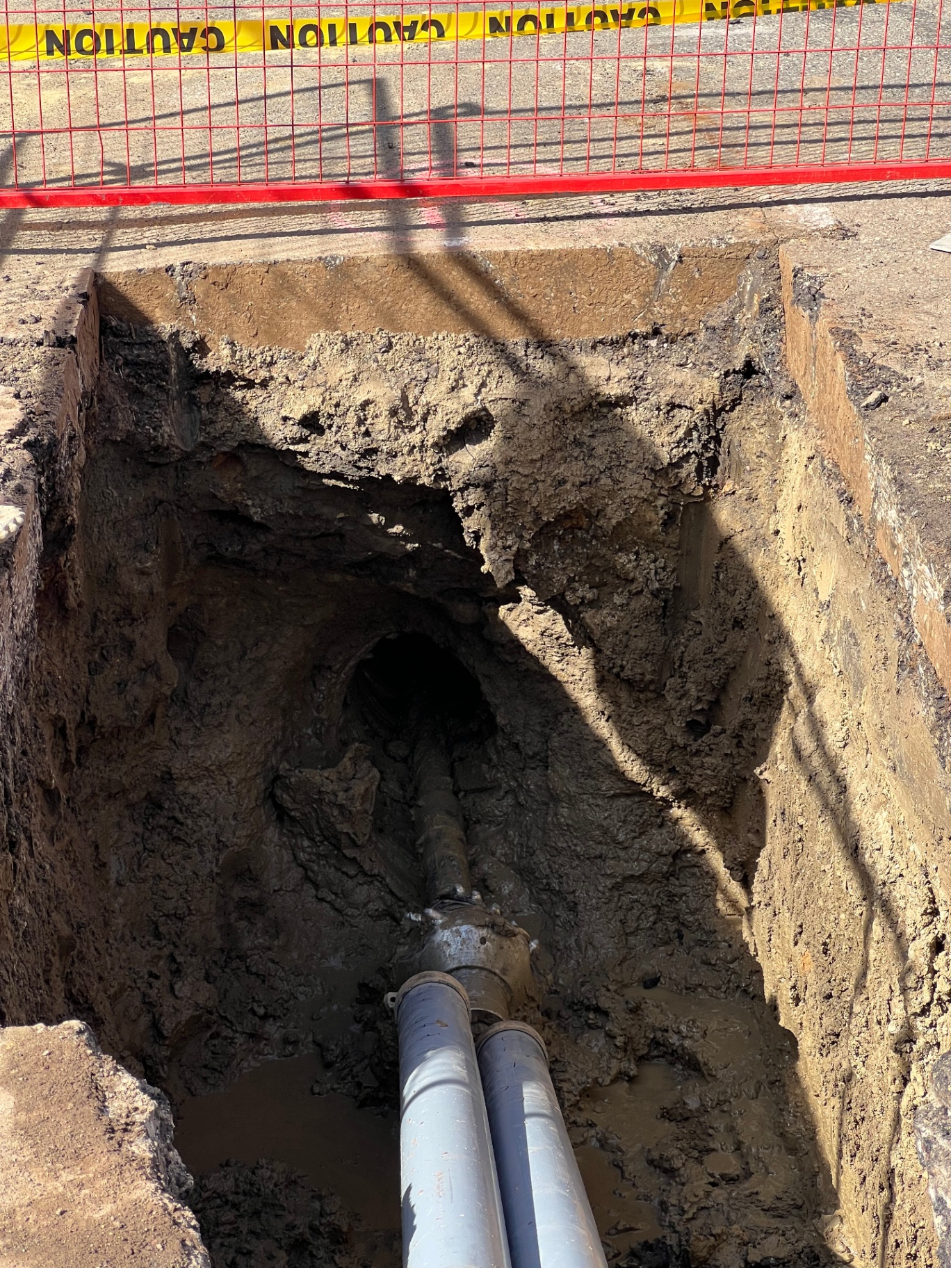 Exposed bore path with conduit pulled through trenchless excavation