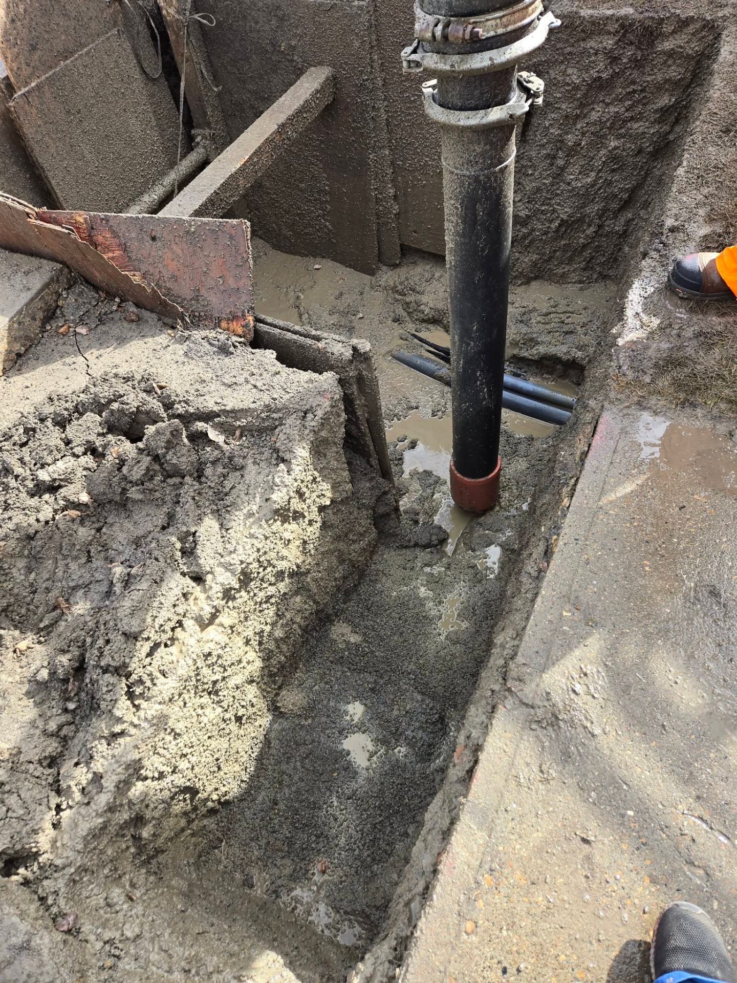 Exposed underground conduits in shored hydrovac potholing excavation